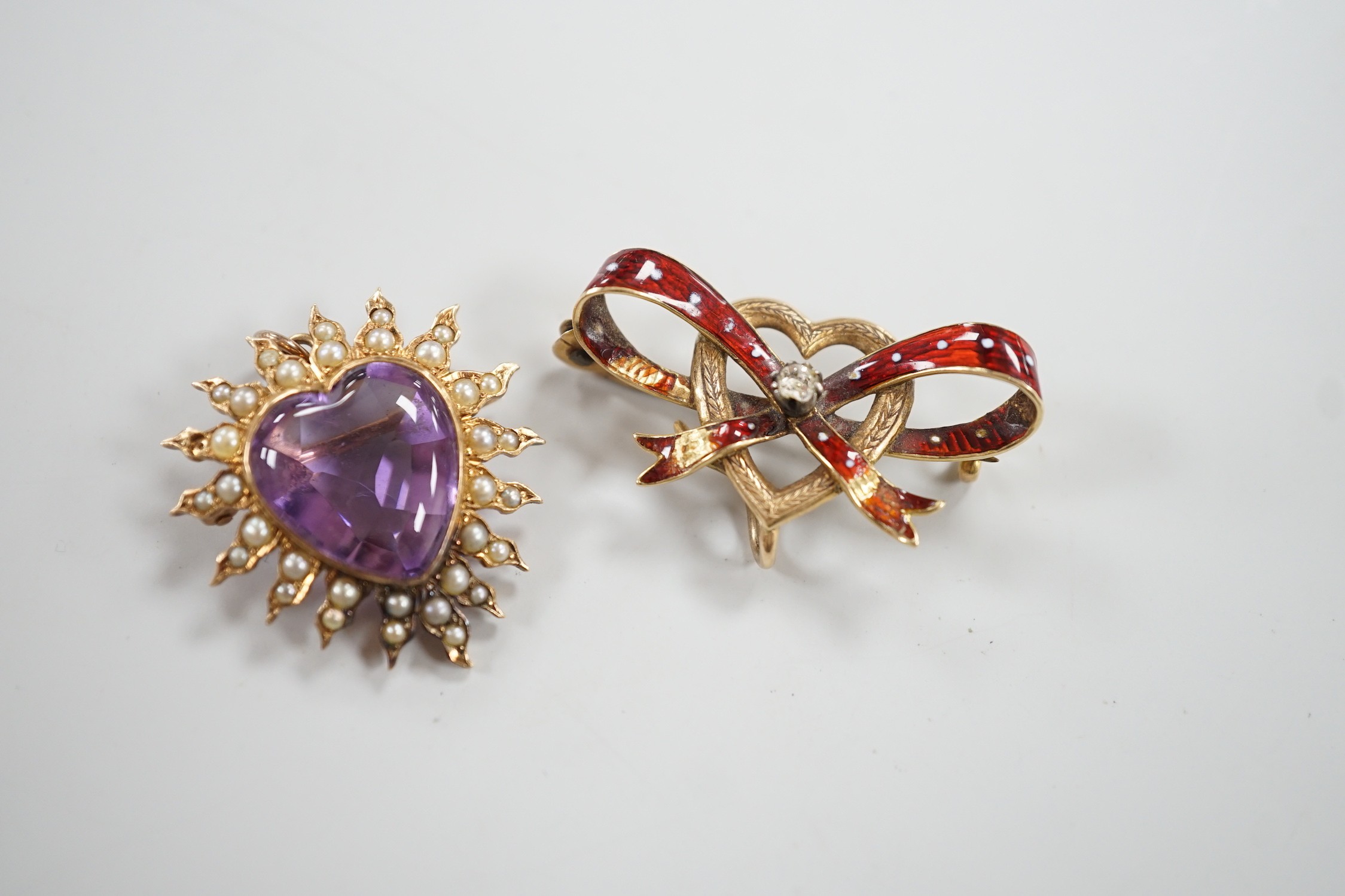 An early 20th century yellow metal amethyst and seed peart set heart shaped pendant brooch, 25mm, gross 5.3 grams and a yellow metal and enamel set ribbon bow and heart brooch (enamel a.f.).